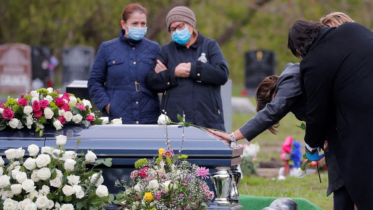 A woman touches the casket of her husband, who died from Covid-19, in Malden, Massachusetts, US. Credit: Reuters File Photo