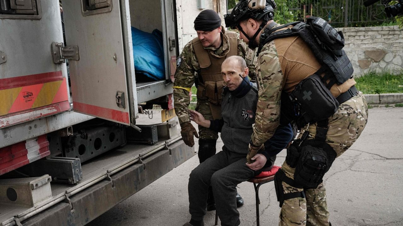 Police officers carry a man on a chair as they help people to get into an armoured vehicle before being evacuated in Lysychansk, eastern Ukraine, amid the Russian invasion of Ukraine. Credit: AFP Photo