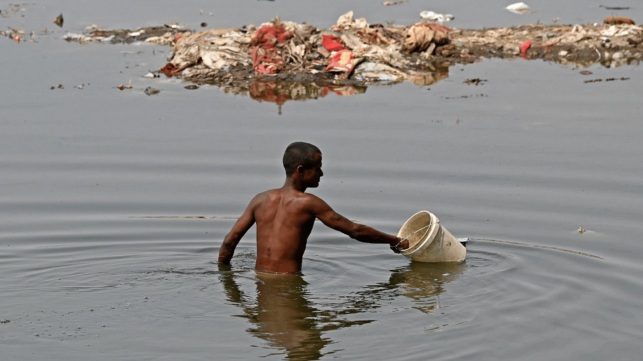 A man looks for reusable items in river Yamuna on a hot summer day in New Delhi. Credit: AFP Photo