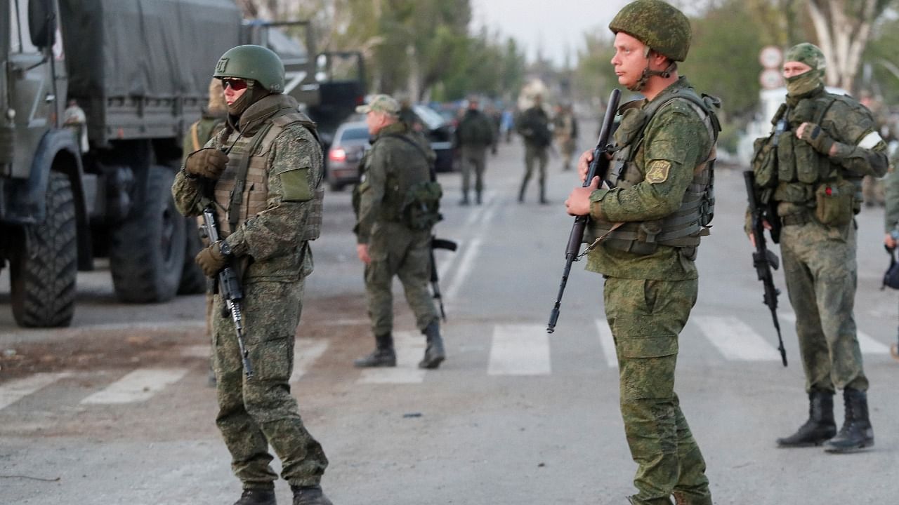 Service members of pro-Russian troops stand guard on a road before the expected evacuation of wounded Ukrainian soldiers from the besieged Azovstal steel mill in the course of Ukraine-Russia conflict in Mariupol. Credit: Reuters File Photo