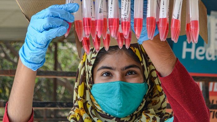 A health worker with swab samples of people collected for Covid-19 test, in Gurugram, Friday, February 18, 2022. Credit: PTI Photo