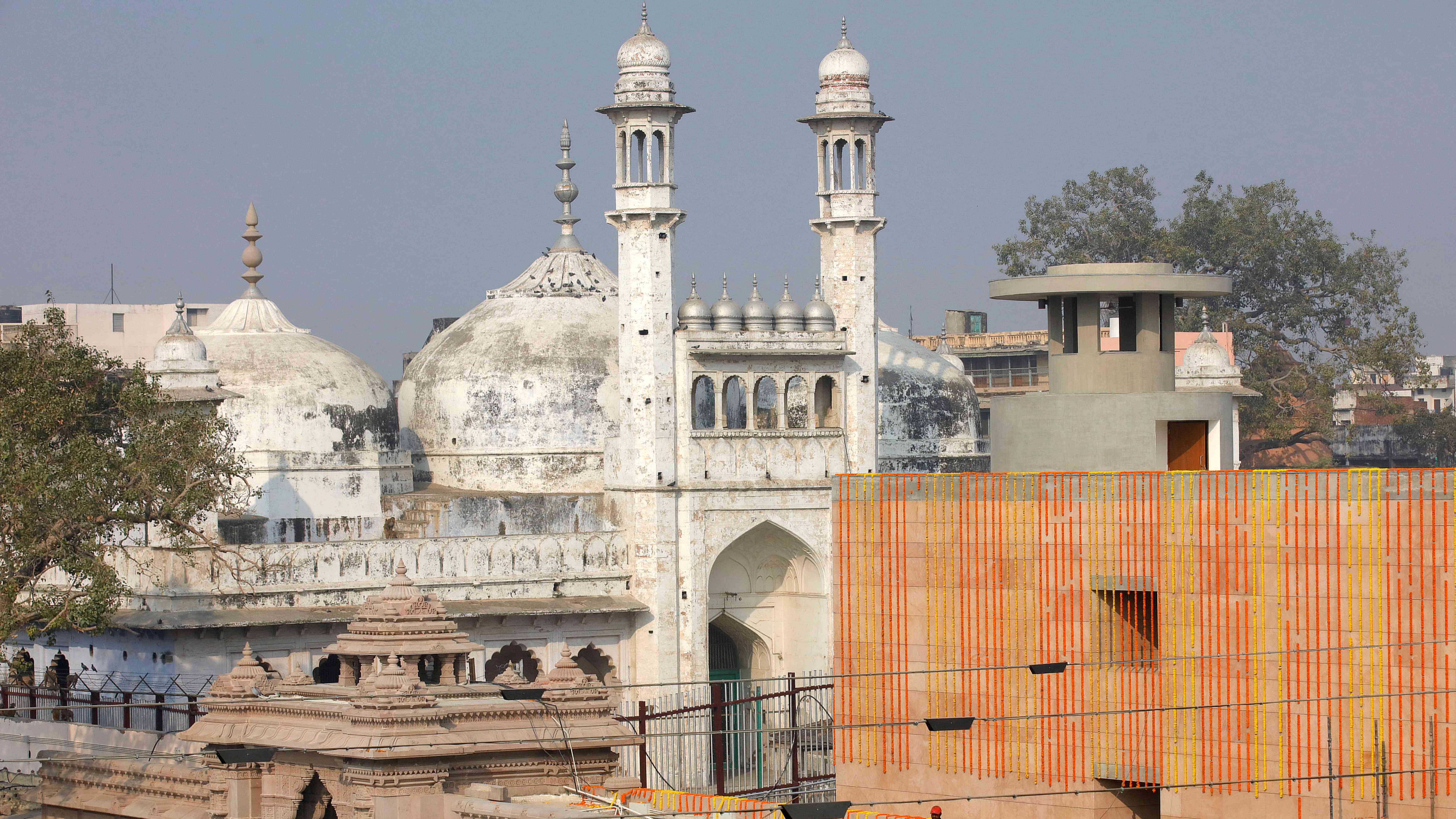  A worker stands on a temple rooftop adjacent to the Gyanvapi Mosque. Credit: Reuters File Photo