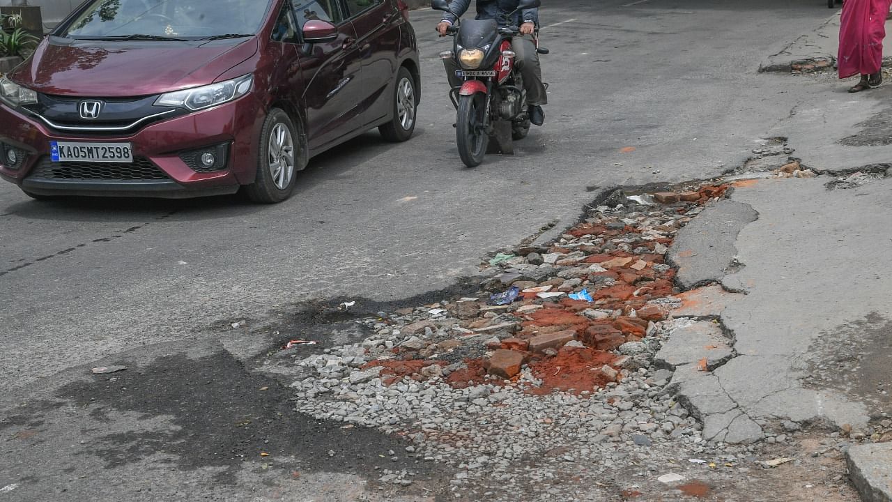 Building debris is filled to pot hole at Bannerghatta Main Road. Credit: DH Photo