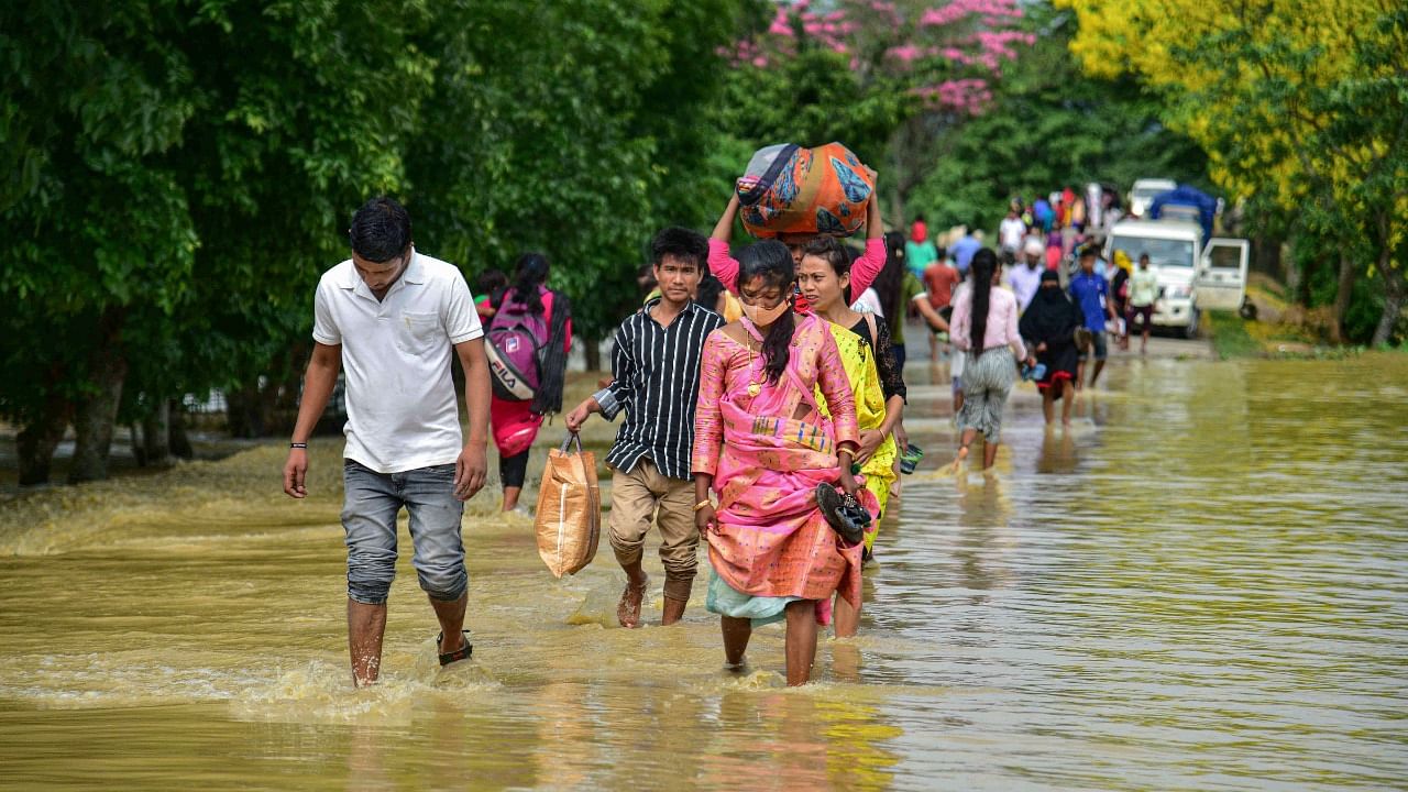 Villagers wade through a flooded road after rain at a village in Nagaon District. Credit: PTI Photo