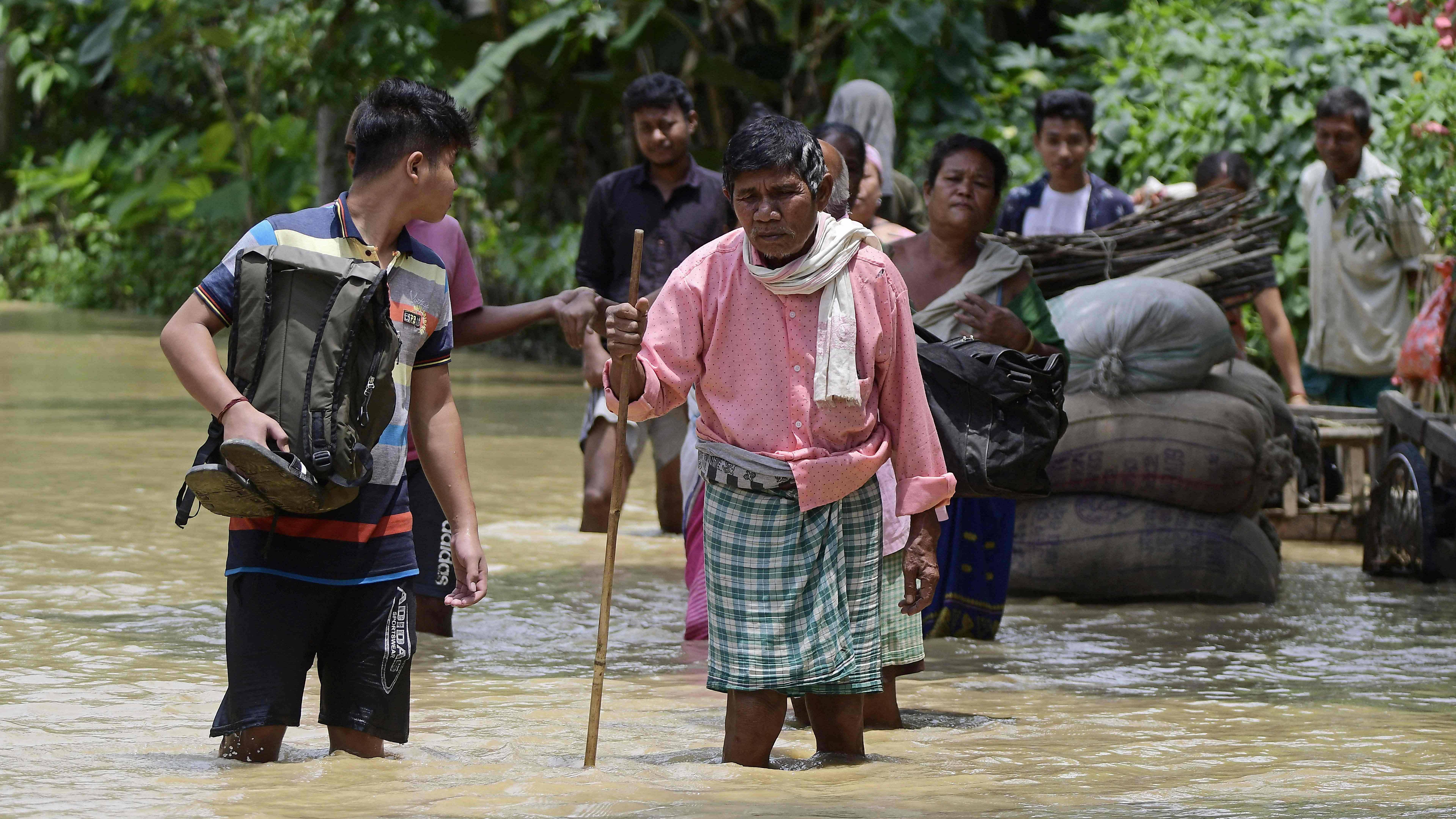 People wade through the flood waters in Nagaon district. Credit: AFP Photo