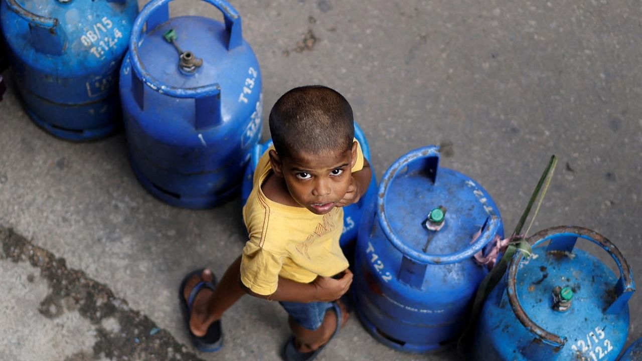 A boy stands next to empty cylinders as he waits in a queue to buy domestic gas at a distribution centre, amid the country's economic crisis, in Colombo. Credit: Reuters photo