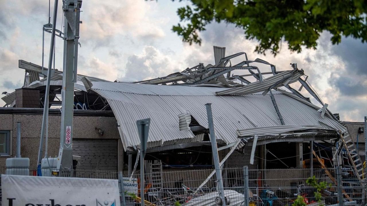 The roof of a construction machinery dealership lies across the building in Paderborn, western Germany on May 20, 2022, after a storm caused major damage. Credit: AFP Photo