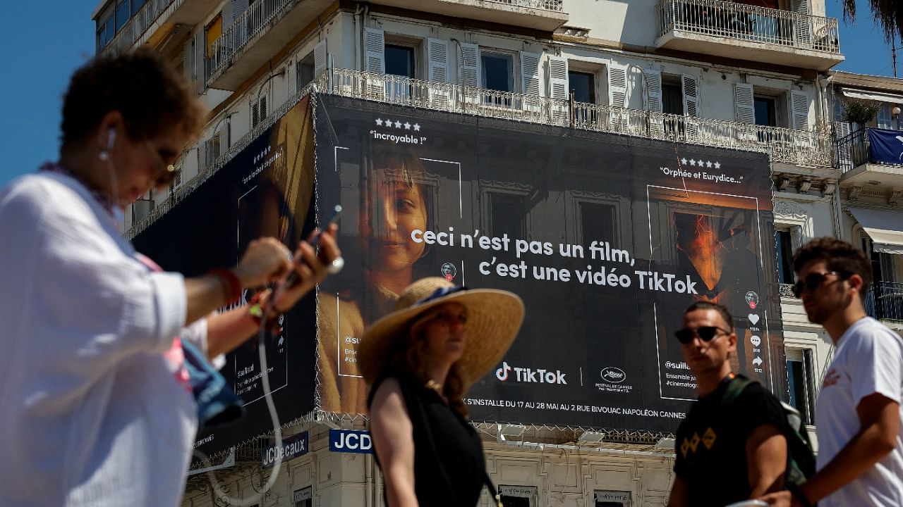 People walk past an advertising poster for TikTok app displayed on the Croisette during the Cannes Film Festival. Credit: Reuters Photo