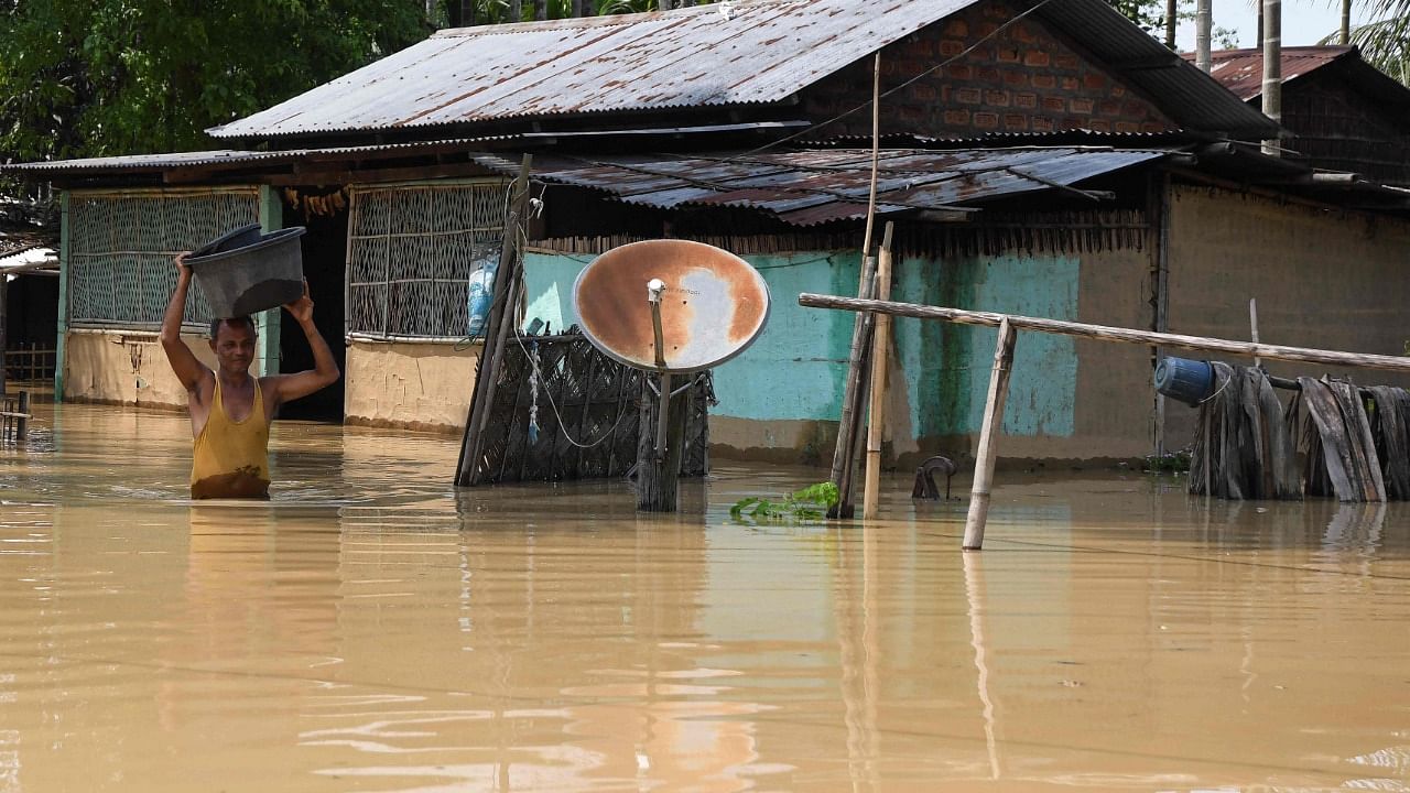 A man carries his belongings through a flooded area after heavy rains in Morigaon district of India's Assam. Credit: AFP Photo
