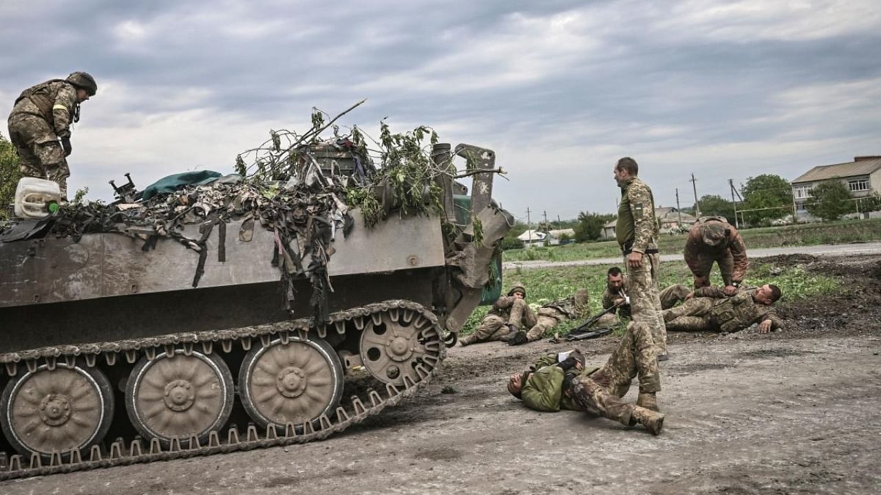 Ukrainian servicemen assist their comrades not far from the frontline in the eastern Ukrainian region of Donbas. Credit: AFP Photo