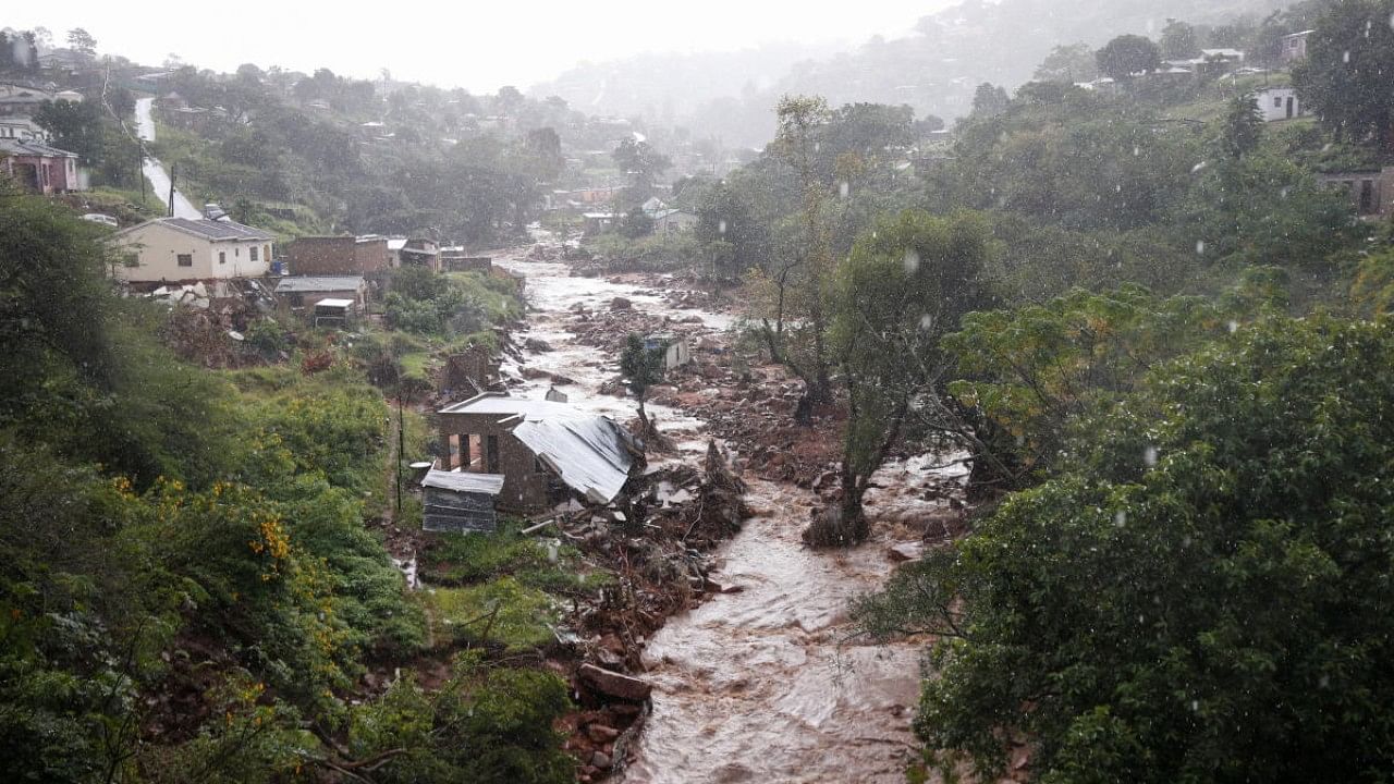 A river runs high after heavy rains, next to homes which were damaged during previous flooding, in kwaNdengezi. Credit: Reuters Photo