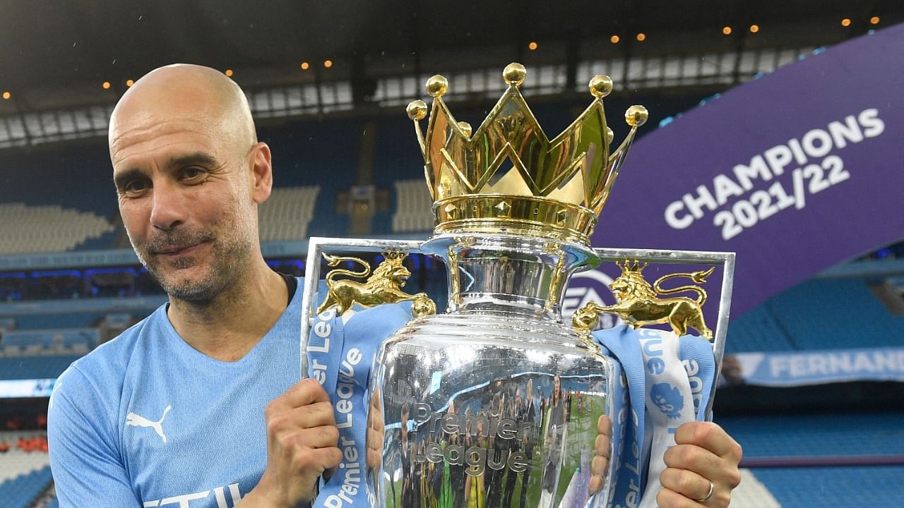 Manchester City's manager Pep Guardiola celebrates with the Premier league trophy on the pitch after the English Premier League football match between Manchester City and Aston Villa at the Etihad Stadium in Manchester. Credit: AFP Photo