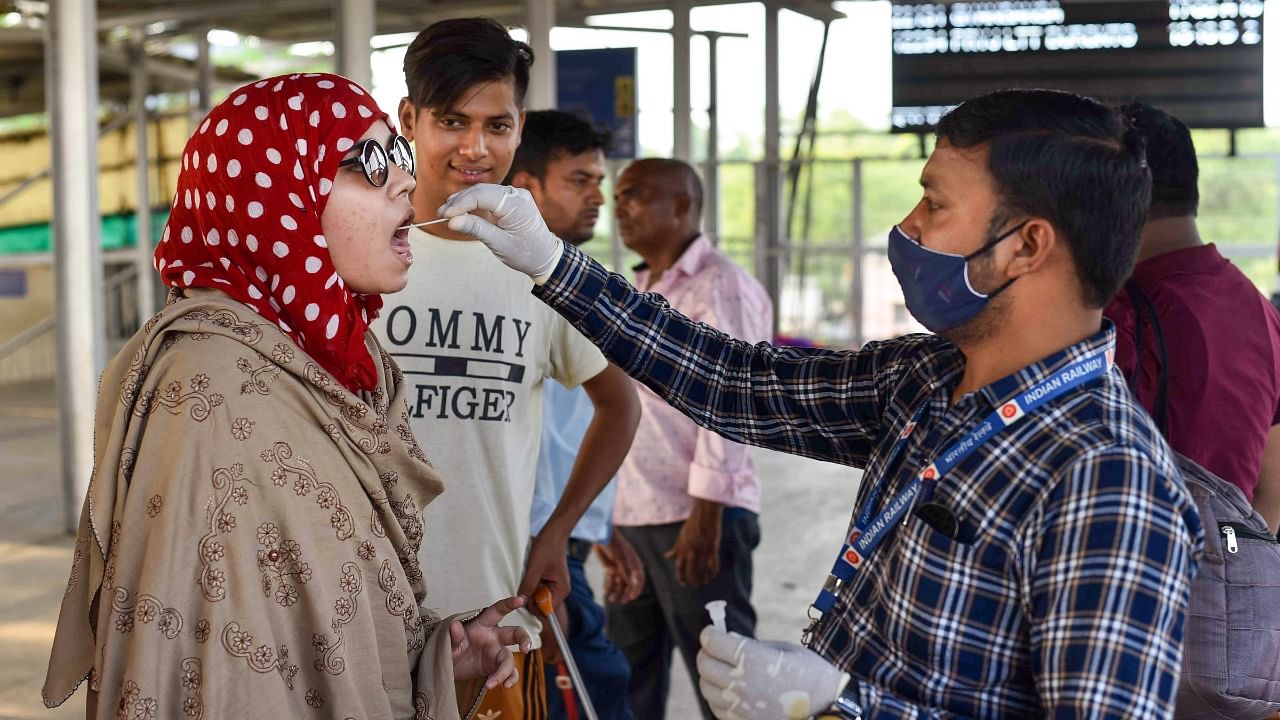  healthcare worker collects a swab sample from a passenger for Covid-19 testing amid a surge in coronavirus cases. Credit: PTI Photo