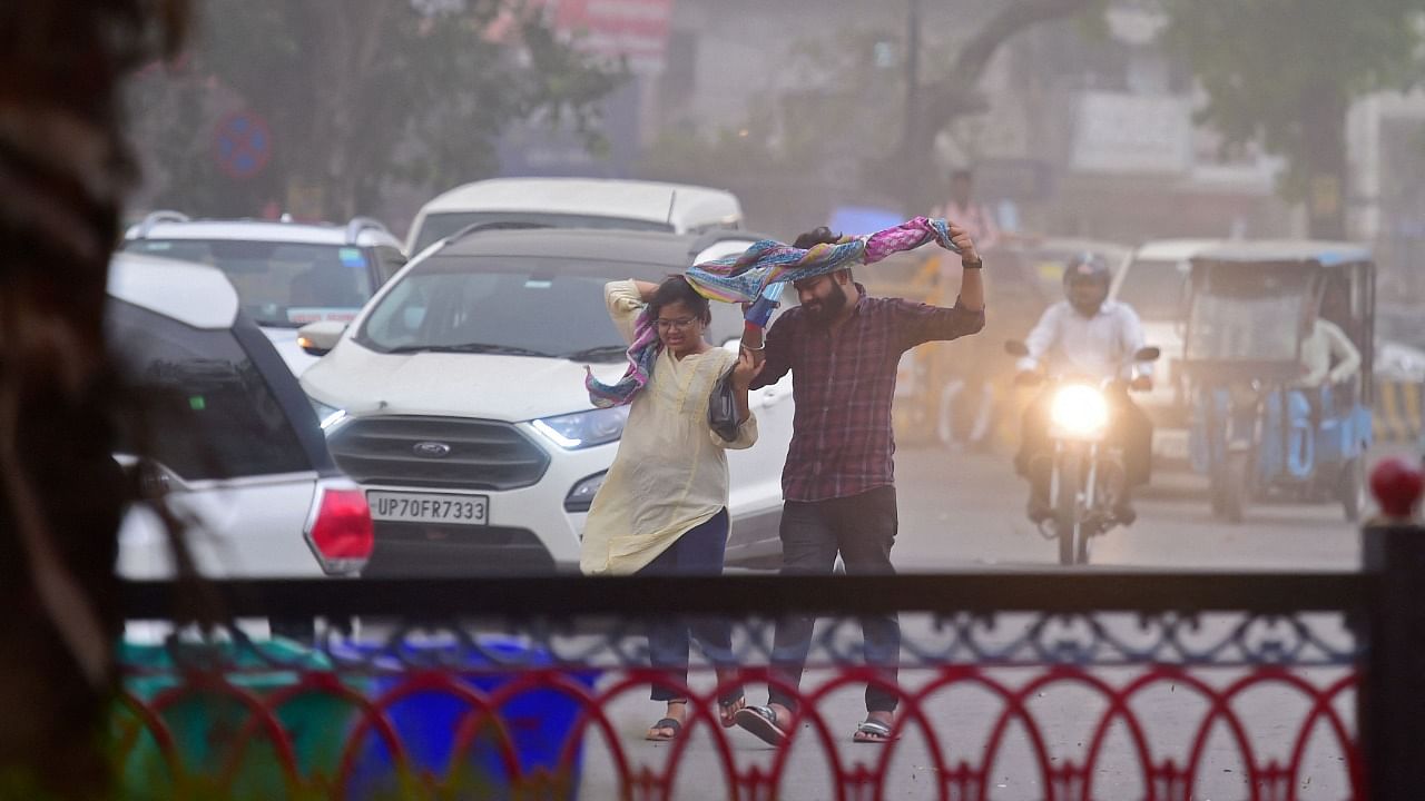 Commuters make their way through a street during strong winds in Allahabad. Credit: AFP Photo