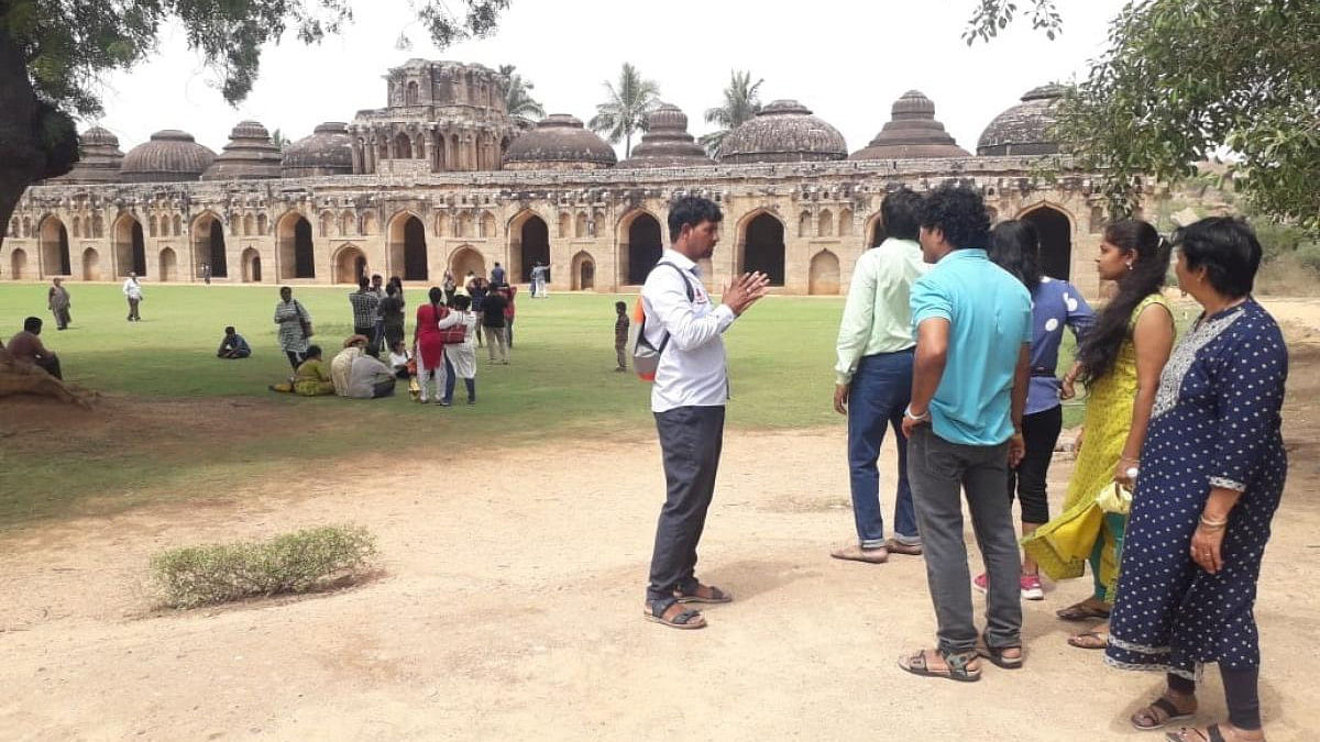 A guide explains the history of the elephant stables to visitors at Hampi. Credit: Special arrangement