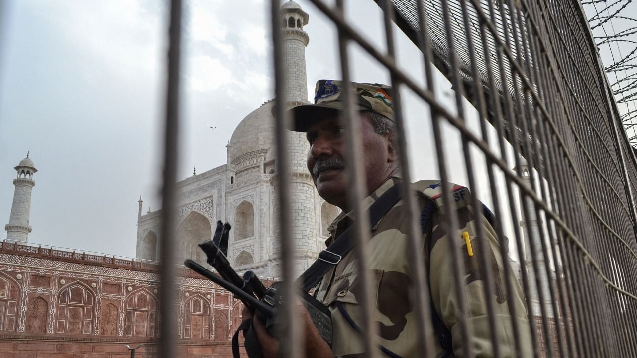 A member of security personnel stands guard behind a perimeter fence at the Taj Mahal in Agra. Credit: AFP Photo