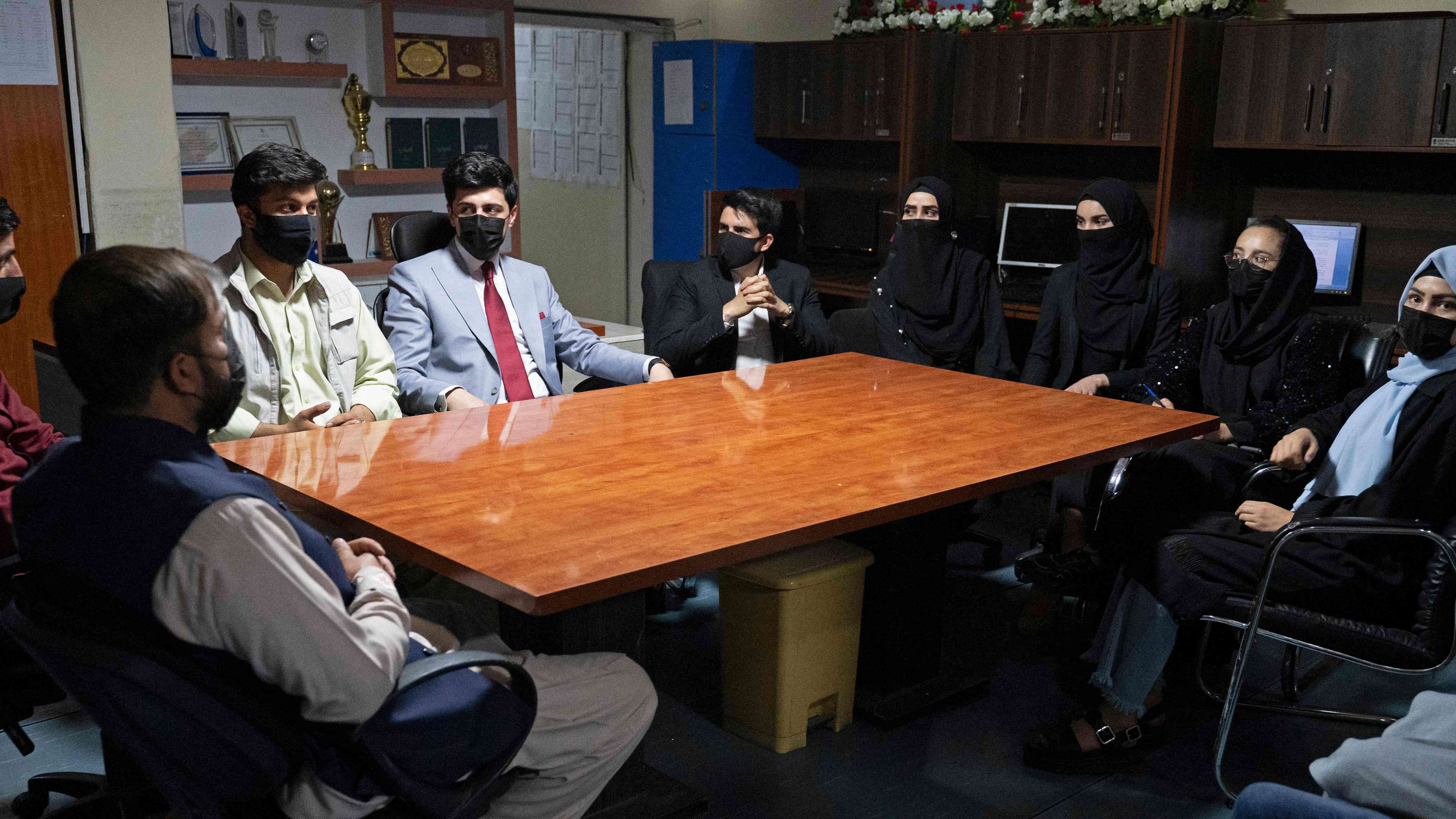 Staff members of 1TV channel, wearing black masks as a symbolic protest against the Taliban authorities for ordering women presenters to cover their faces on air, sit inside their channel's station in Kabul. Credit: AFP Photo