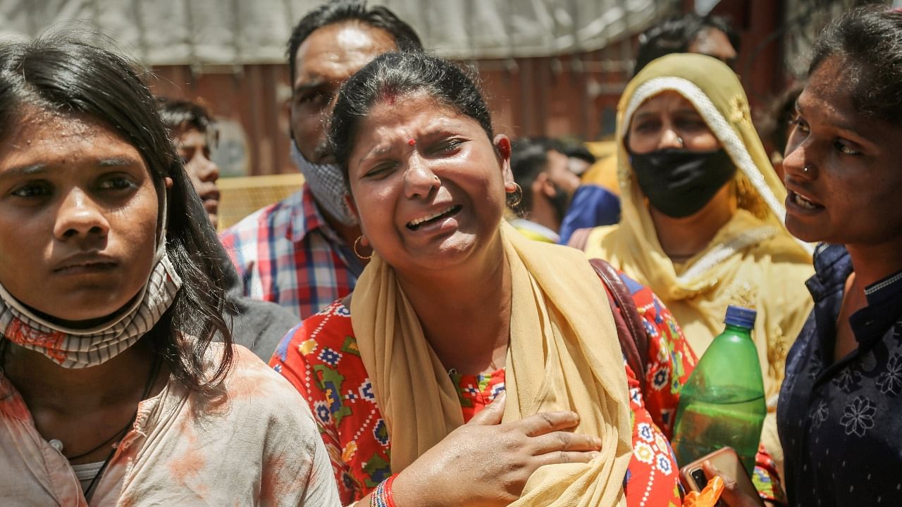 Family members of the people missing after a massive fire at an office building near the Mundka metro station, react as they wait outside the office building at Mundka.  Credit: PTI PHoto