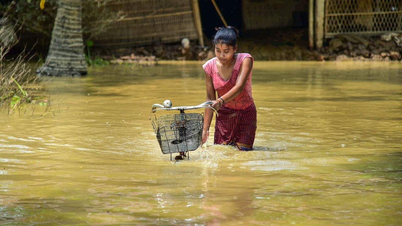 A girls pushes her bicycle as she wades through a flood-affected area in Nagaon district. Credit: PTI Photo
