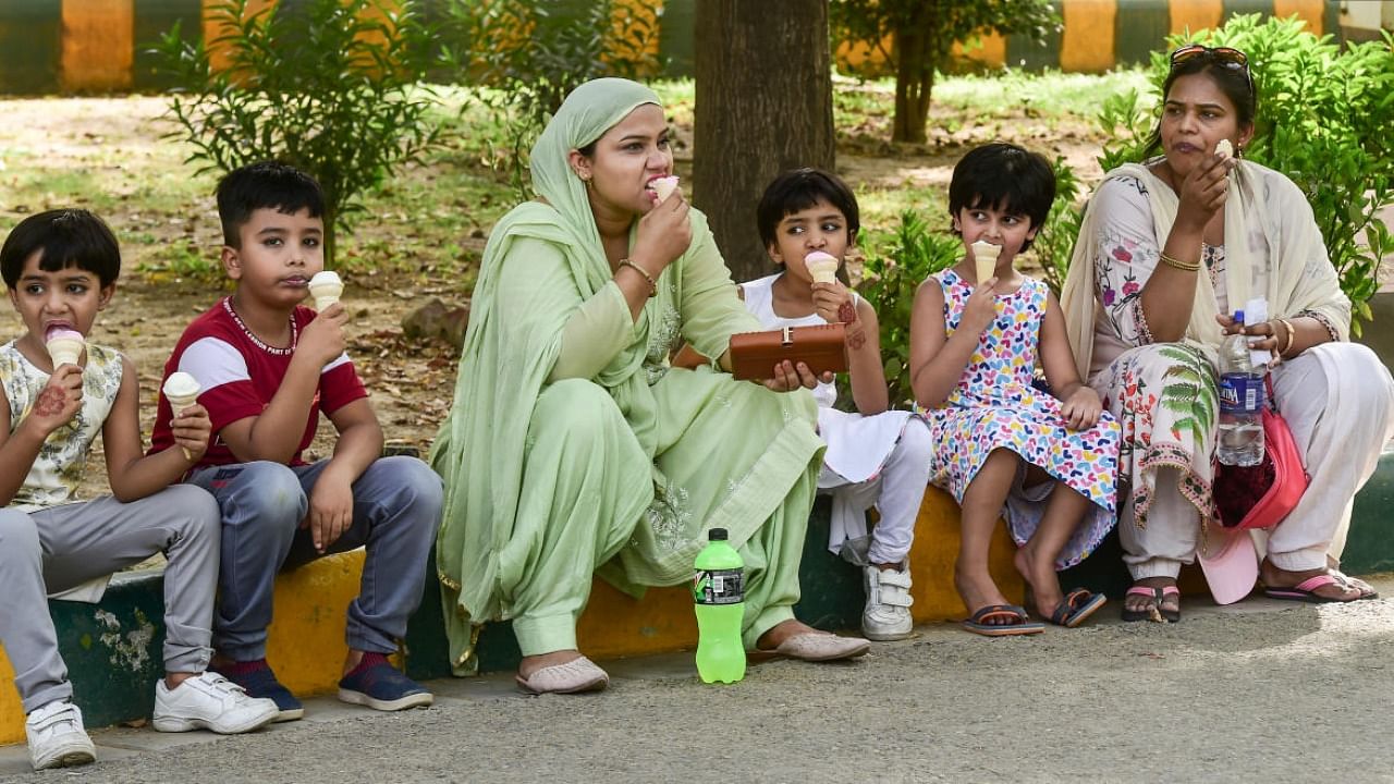People eat ice-creams under the shade of a tree, on a hot summer day in New Delhi. Credit: PTI Photo