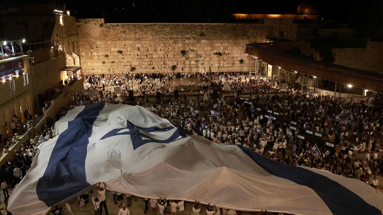 Israelis wave the national flag at the Western Wall in Jerusalem on May 28, 2022, on the eve of the 'flags march' to mark Jerusalem Day, which commemorates the unification of the city after Israel annexed east Jerusalem in 1967. Credit: AFP Photo