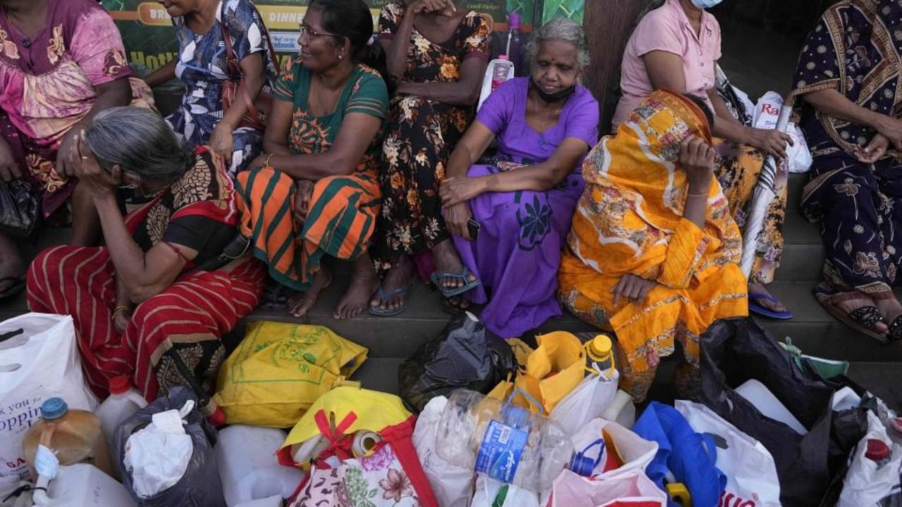 Women wait near an empty fuel station hoping to buy kerosene oil for cooking in Colombo, Sri Lanka, Thursday, May 26, 2022. Credit: AP/PTI Photo