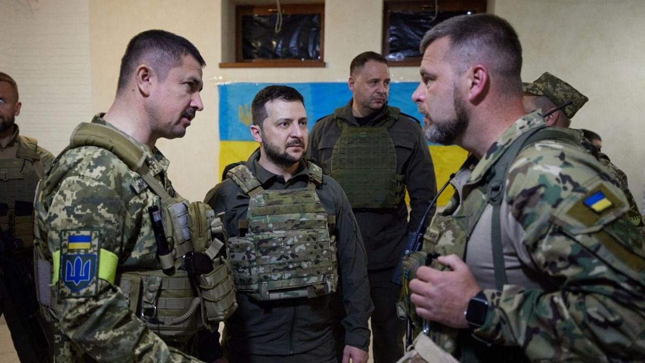 This handout picture taken and released by the Ukrainian Presidential press-service on May 29, 2022 shows Ukrainian President Volodymyr Zelenskyy (C) talking with servicemen during his visit to the Kharkiv region. Credit: AFP Photo