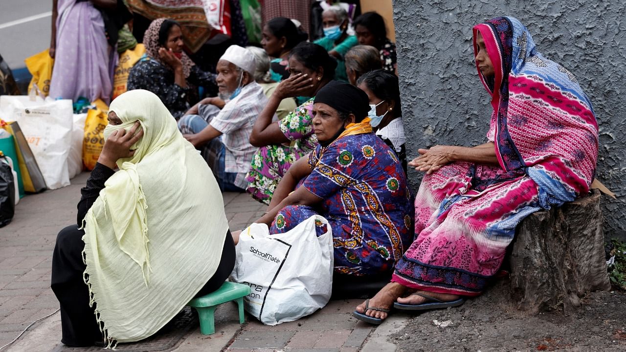 People wait on a pavement near a distributor to buy kerosene oil for their cookers due to domestic gas shortage, amid the country's economic crisis, in Colombo, Sri Lanka. Credit: Reuters Photo