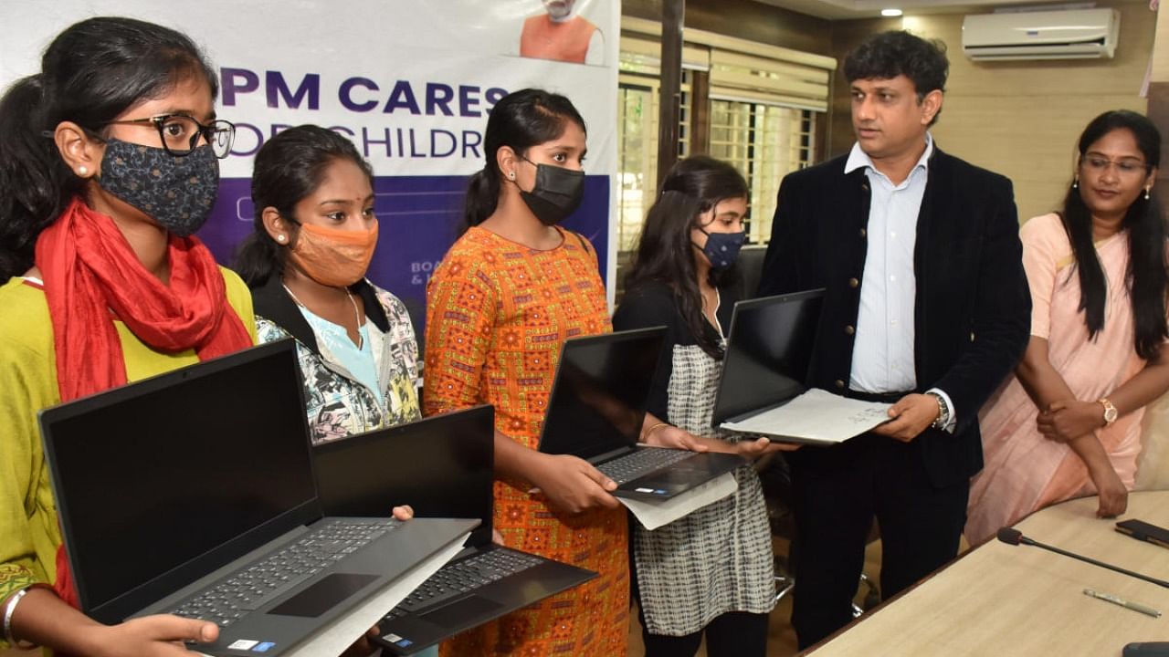 Deputy Commissioner J Manjunath distributes laptops to students in Bengaluru on Monday. Credit: DH Photo/B K Janardhan