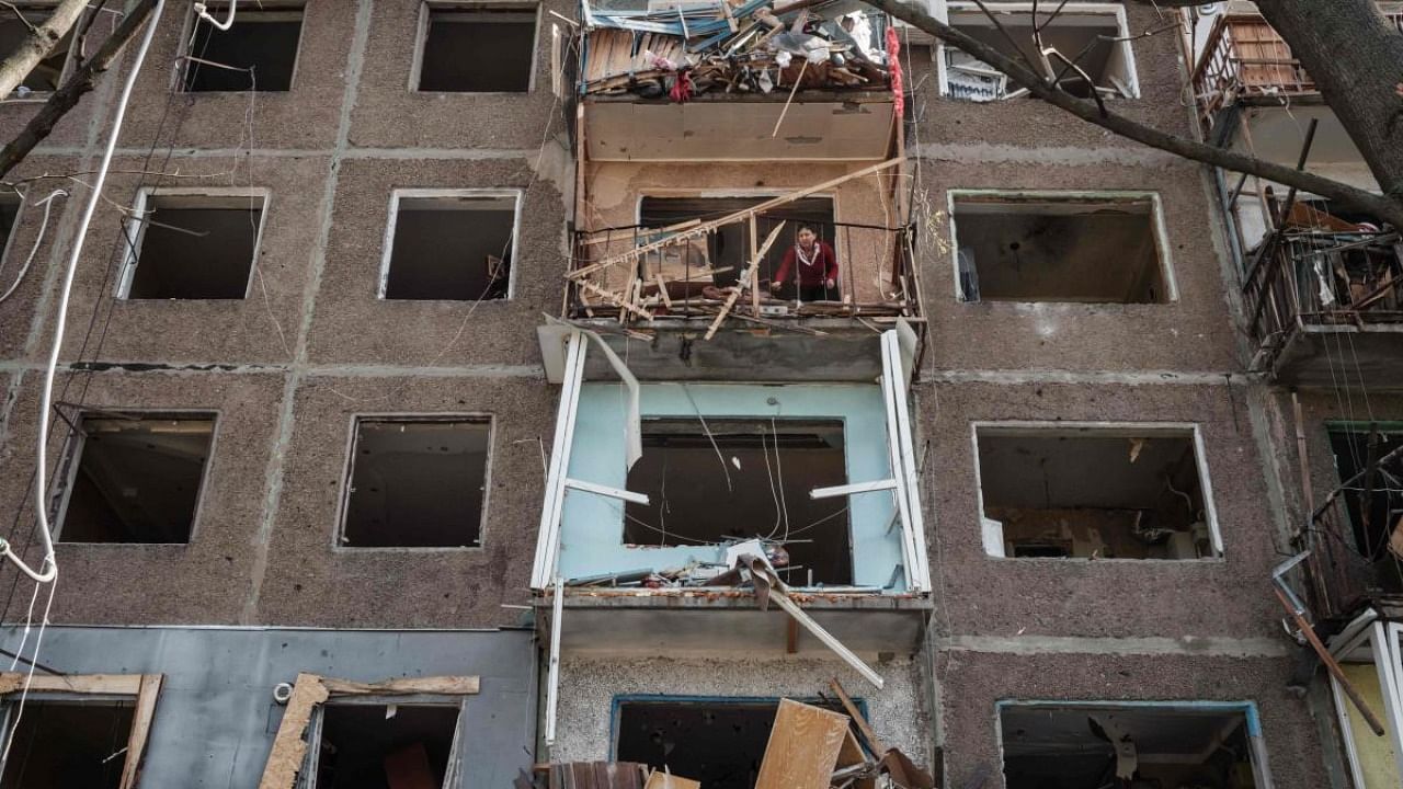 A woman on a balcony cleans her room at an apartment damaged by a missile explosion in Kramatorsk. Credit: AFP Photo