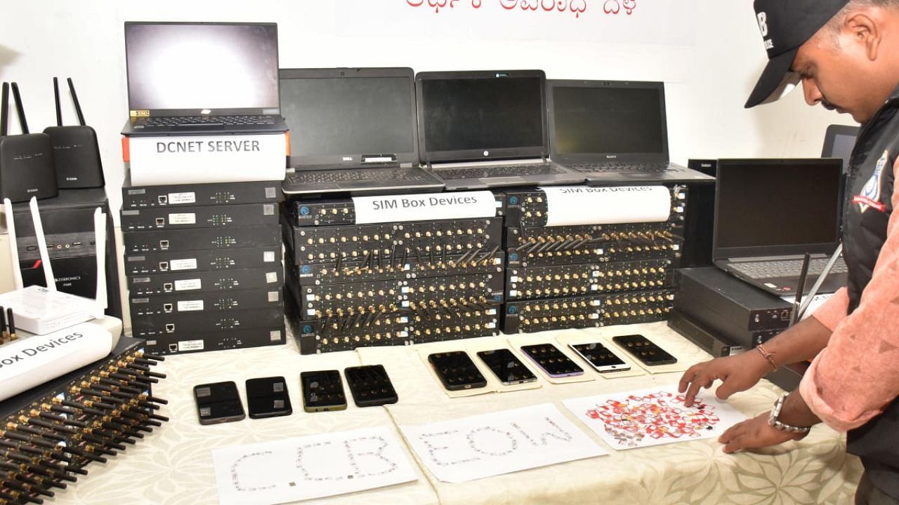 A CCB official displays the seized devices during a press conference at the police commissioner's office in Bengaluru on Wednesday. Credit: DH Photo/B K Janardhan