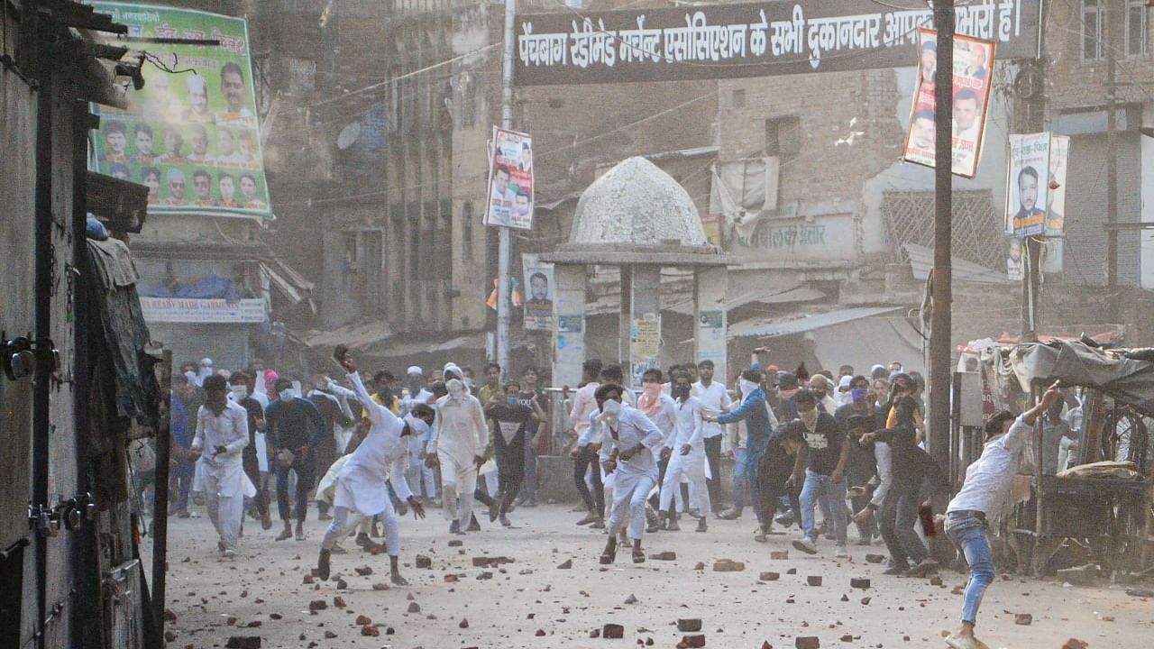 Members of the Muslim community throw stones during clashes after a Muslim organisation called to shut down shops at the Parade Market, in Kanpur. Credit: PTI Photo