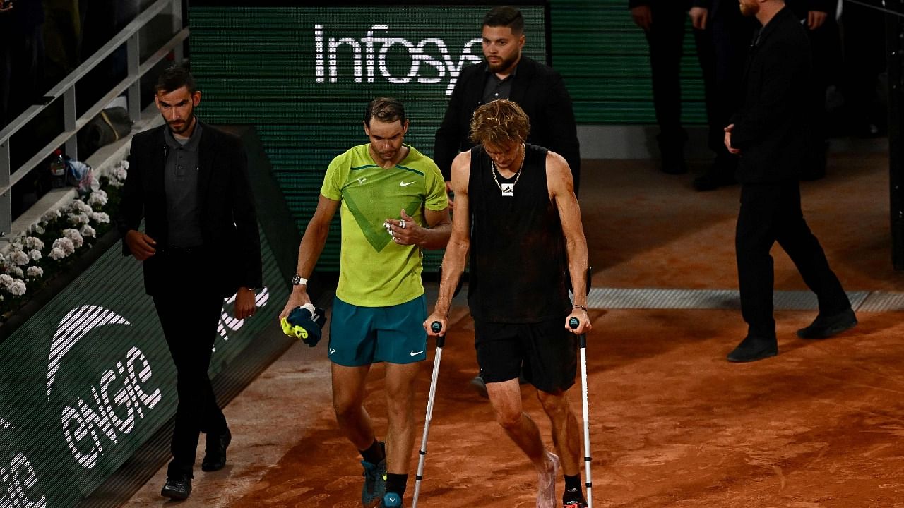 Germany's Alexander Zverev (R)walks with crutches on the court after being injured during his men's semi-final singles match against Spain's Rafael Nadal (L) on day thirteen of the Roland-Garros Open tennis tournament at the Court Philippe-Chatrier in Paris. Credit: AFP Photo