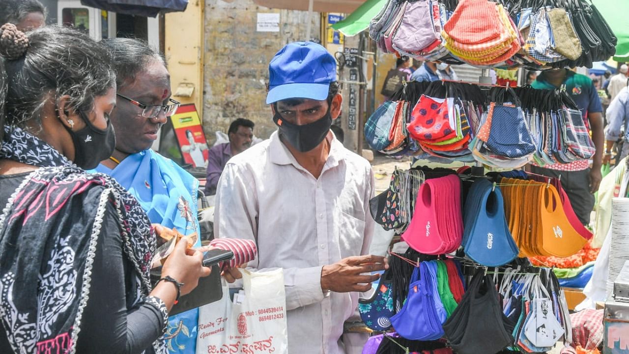Masks are again in demand with the government deciding to enforce compulsory mask rule. A vendor does brisk business in Bengaluru on Saturday. Credit: DH Photo