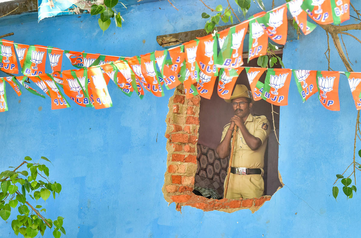 A policeman looks out of a damaged house in RR Nagar during a ceremony on Sunday to lay the foundation stone for the construction of 1,588 houses and the distribution of title deeds. Credit: DH Photo