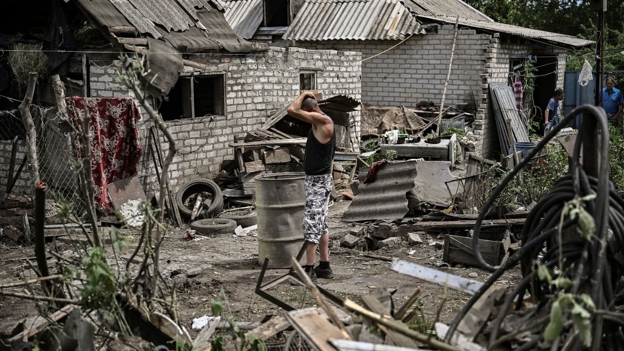 Maksym Katerin stands in the yard of his damaged house after his mother and his step father were killed during shelling in the city of Lysychansk. Credit: AFP Photo