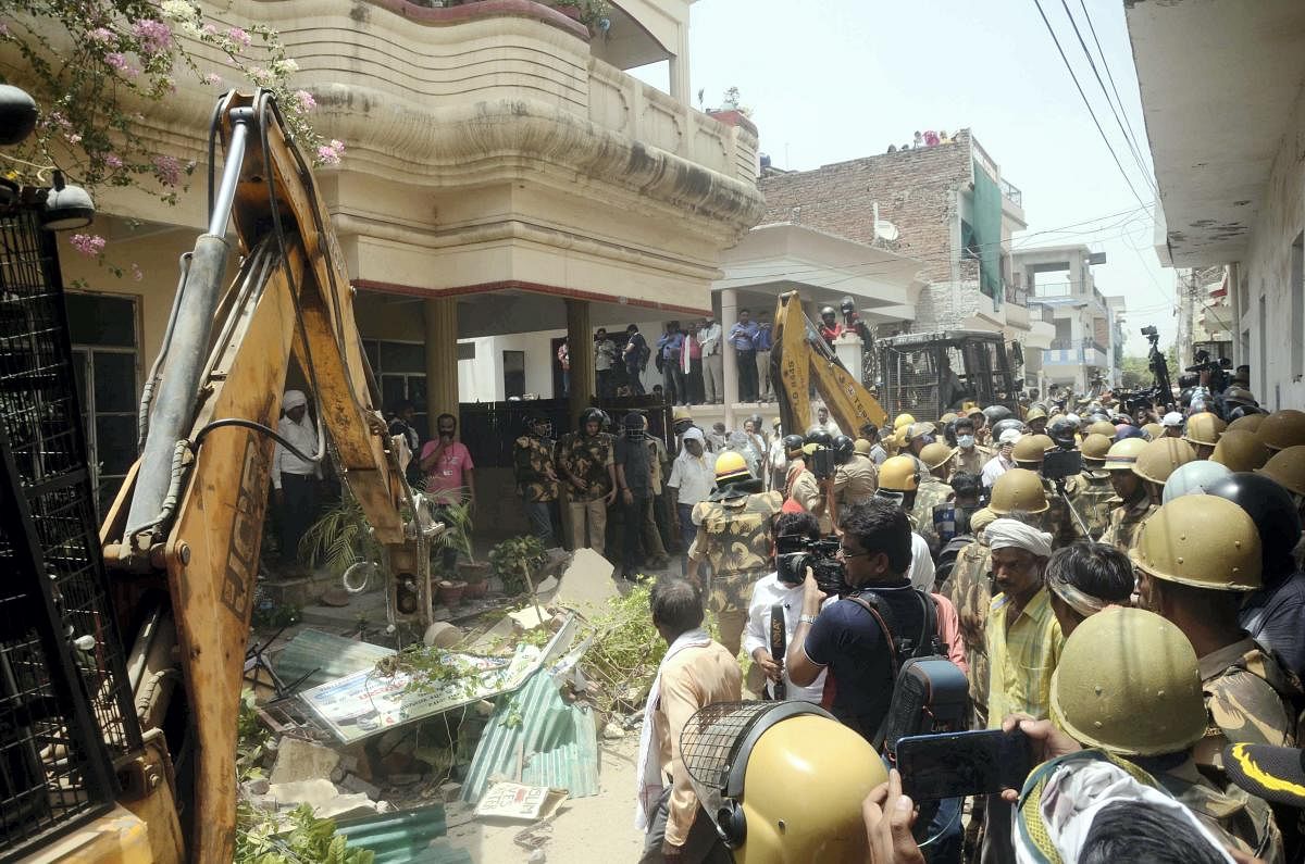  Security personnel and locals gather at the site as a bulldozer is being used to demolish the residence of Javed Ahmed, a local leader who was allegedly the key conspirator of violent protests against now-suspended BJP leaders' remarks on Prophet Muhammad, in Prayagraj, Sunday, June 12, 2022. Credit: PTI Photo