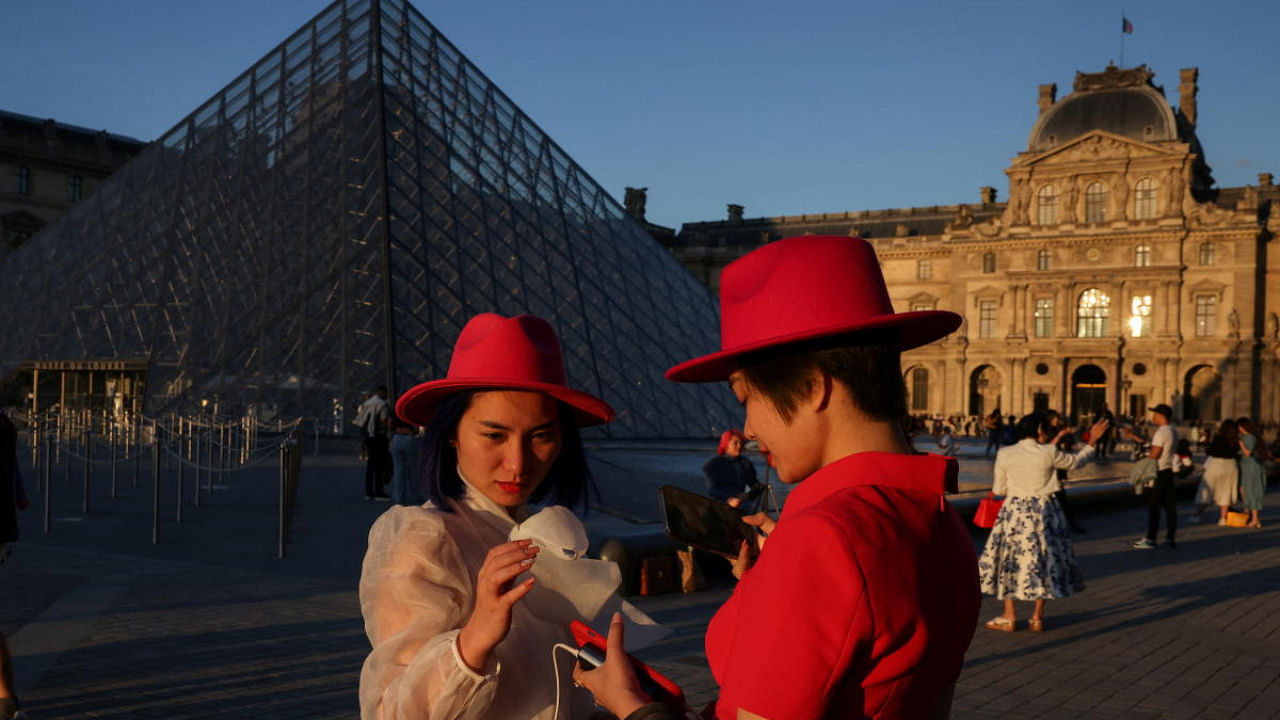Tourists from Vietnam outside the Louvre Pyramid at sunset in Paris. Credit: Reuters photo