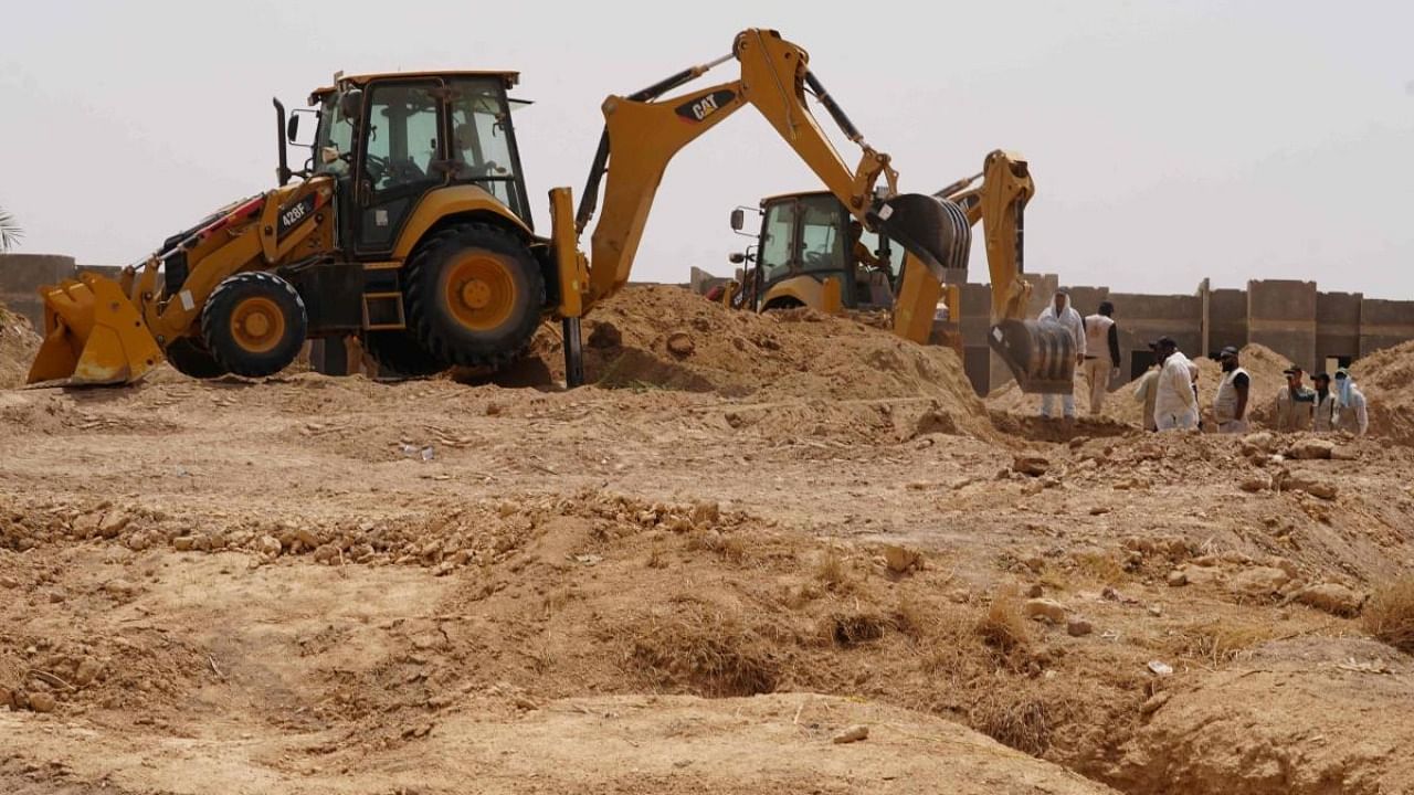 A backhoe digs up earth to uncove at the site of a mass grave, discovered by chance when property developers wanted to prepare the land for construction, in the central city of Najaf, on May 18, 2022. Credit: AFP Photo