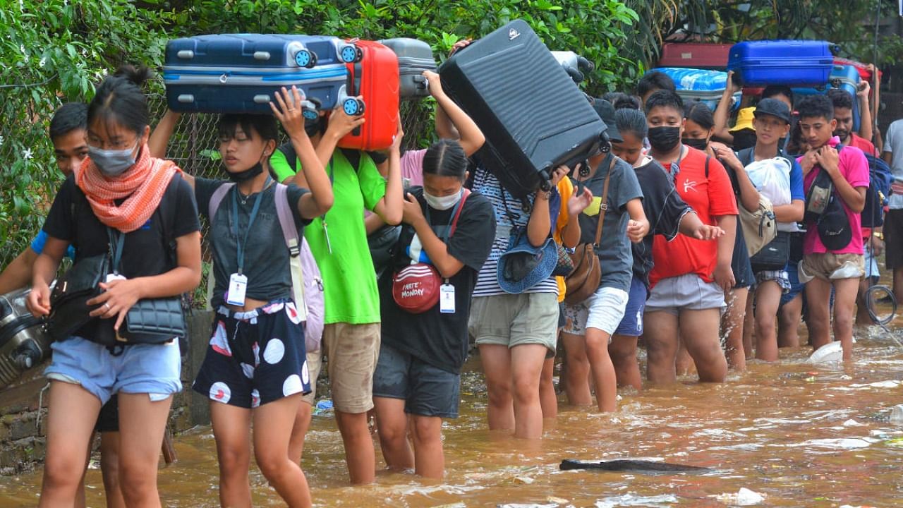 Students carry their belongings after their hostels and accommodations were flooded due to rains in Guwahati on Wednesday. Credit: PTI Photo