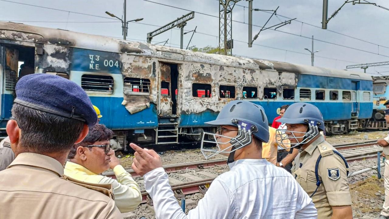 Security personnel investigate after youngsters set on fire train in protest against the 'Agnipath' scheme, at Chapra Railway Station, in Saran district. Credit: PTI Photo