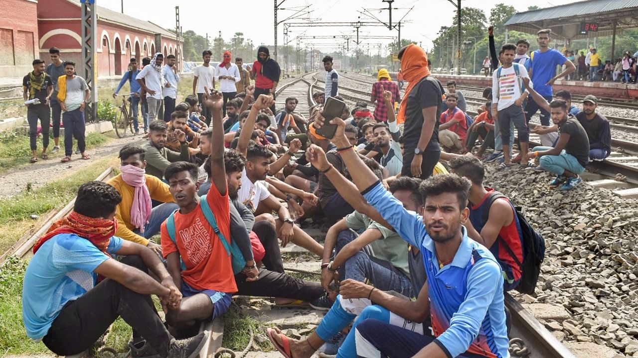 Youngsters sit on railway tracks to protest against the 'Agnipath' scheme, in Buxar. Credit: PTI Photo