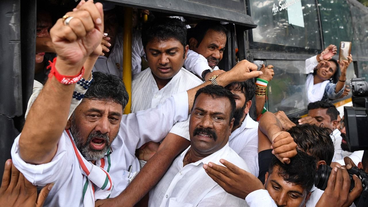 President of Karnataka State Congress, D.K. Shivakumar (L) shouts slogans and raises his hand after being detained by police in Bangalore. Credit: AFP Photo