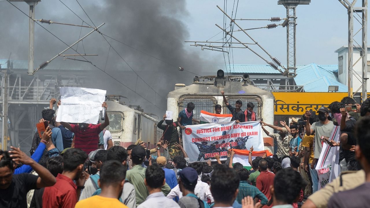 Protesters shout slogans after setting a train on fire during a demonstration against the government's new 'Agnipath' recruitment scheme for the army, navy, and air forces at a railway station in Secunderabad. Credit: AFP Photo
