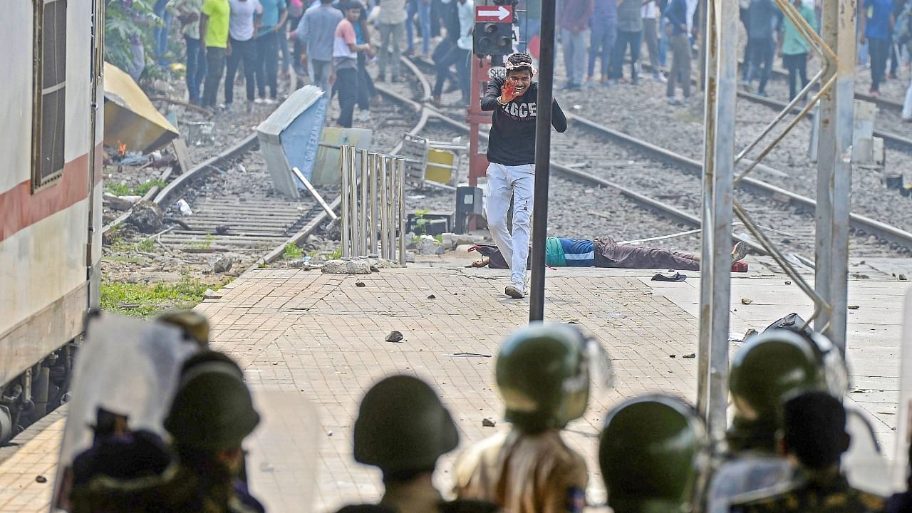 A protestor reacts in front of a wounded man after police opened fire to disperse protestors during a demonstration against the government's new 'Agnipath' recruitment scheme in Secunderabad. Credit: AFP Photo 