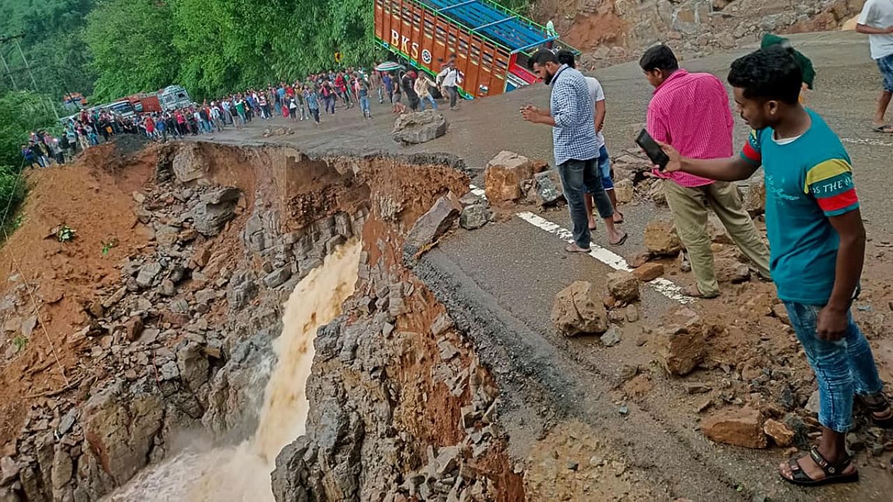 People gather near a truck after it crashed as some part of the National Highway 6 (NH06) under Lumshnong Police Station's jurisdiction caved in due to a landslide after heavy rains, in Meghalaya's East Jaintia Hills district. Credit: PTI Photo