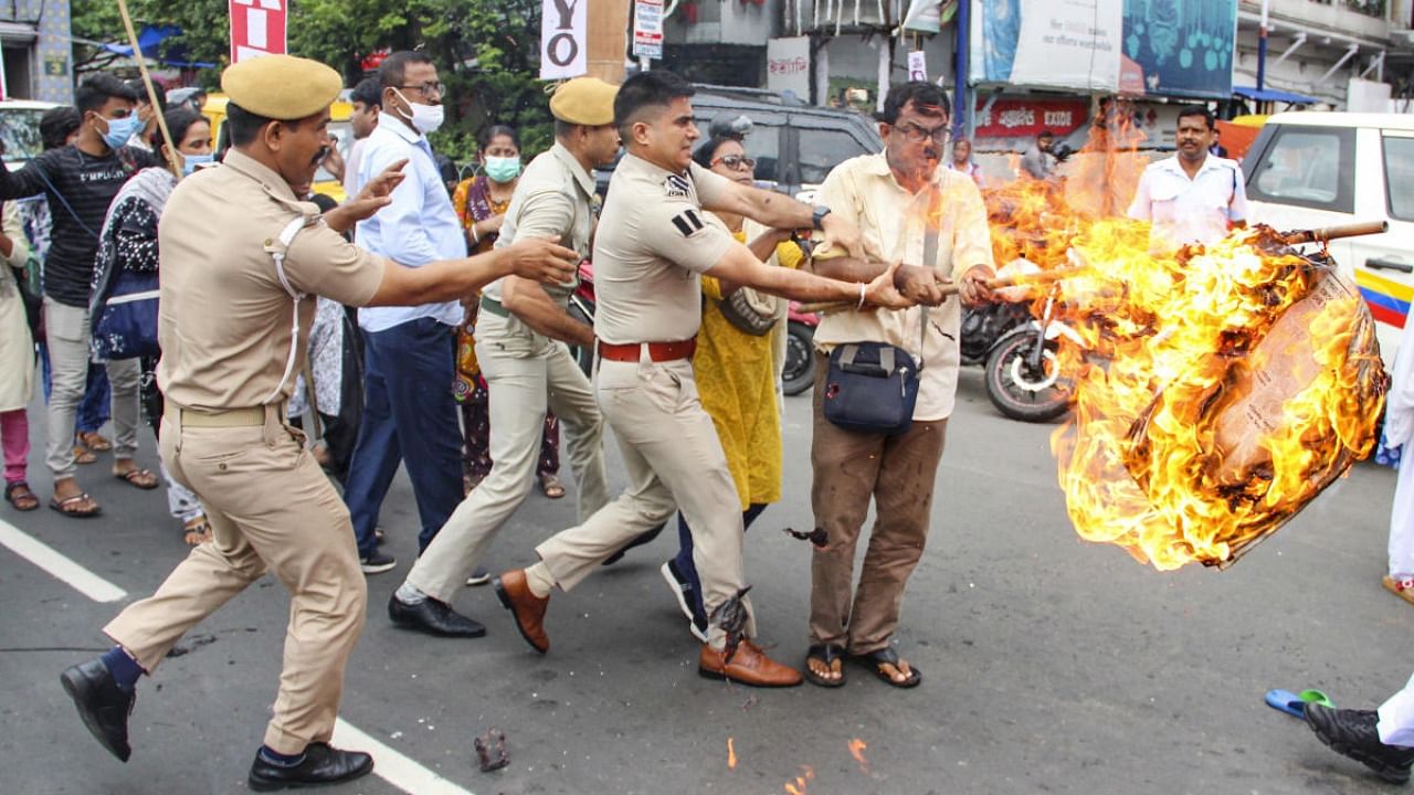 Police personnel try to snatch a burning effigy from a protester during a protest against the Agnipath scheme, in Kolkata. Credit: PTI photo