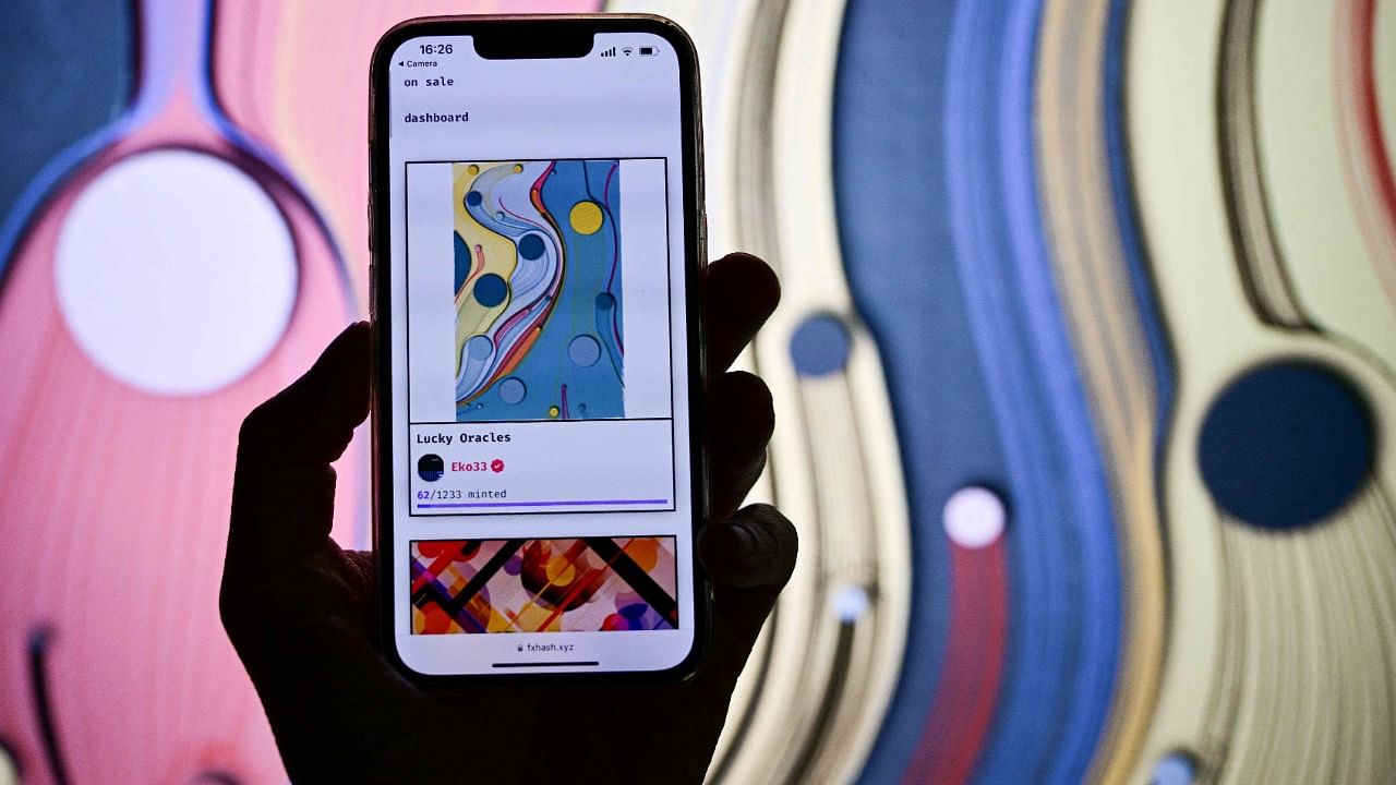 A visitor holds a cell phone displaying a virtual art piece sells by NFT during a preview day of Art Basel. Credit: AFP Photo