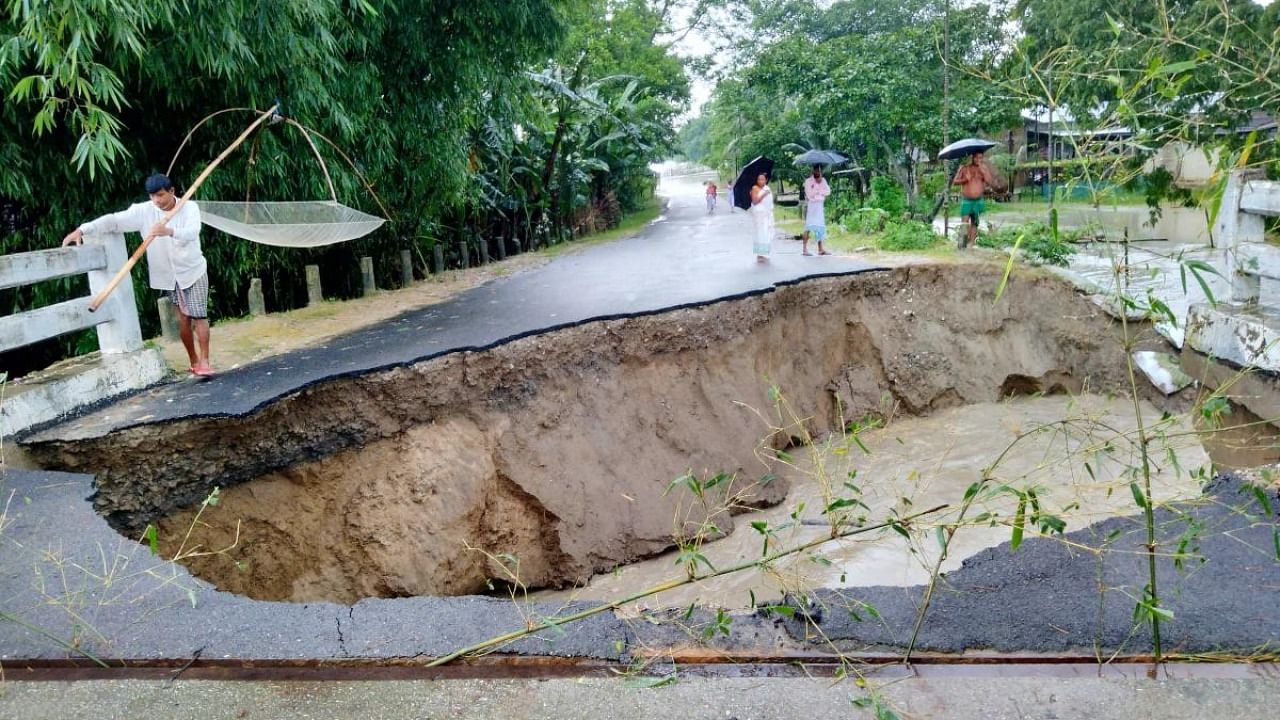 Locals inspect the flood-damaged Dhamdhama-Khatikuchi connecting road following heavy rains, in Baksa district. Credit: PTI Photo