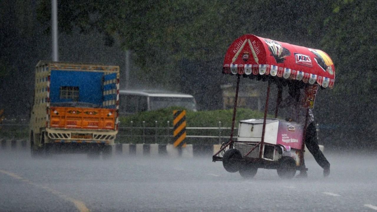 An ice cream vendor pushes his cart through a street during a heavy rain shower in Chennai on December 30, 2021. Credit: AFP Photo